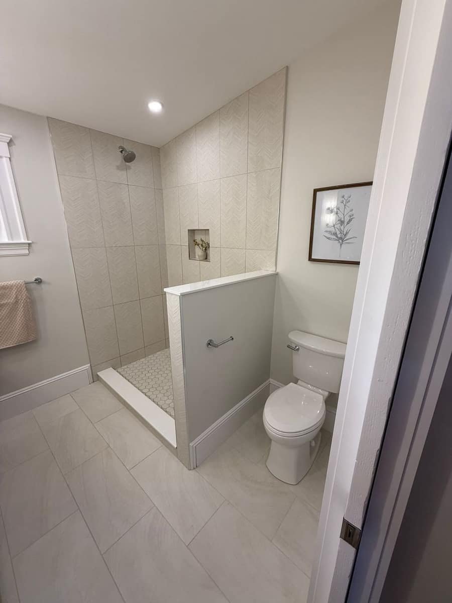White tiled bathroom with new shower drain and fixtures installed by Precision Plumbing Solutions